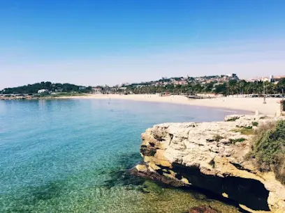 Playa de l'Arrabassada en Tarragona con arena dorada, aguas tranquilas y familias disfrutando